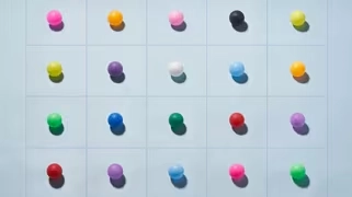 Tableau de boutons colorés en rangées, représentant la diversité et la modularité des modèles de conception d'expérience Homme-IA