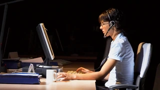 Professionnelle en informatique travaillant dans un bureau sombre, illustrant l'engagement dans la conception d'une IA conversationnelle